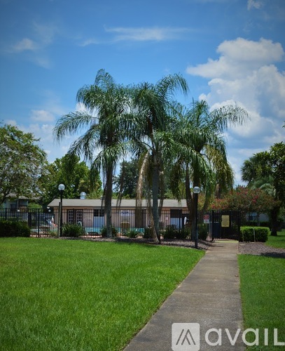 A walkway leads through a grassy area with palm trees.