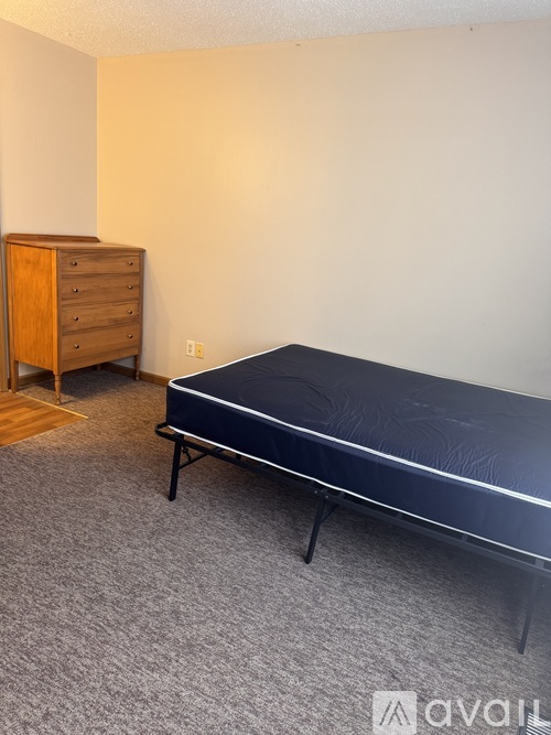 A bedroom with a bed, dresser and carpet.
