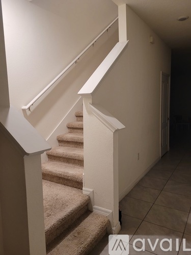 A staircase with a beige carpeted runner and white risers.