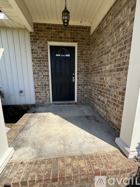A black door is set in a brick wall.