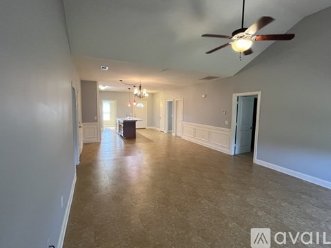A spacious room with a ceiling fan and a chandelier.
