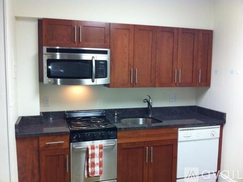 A kitchen with a black counter top and wooden cabinets.