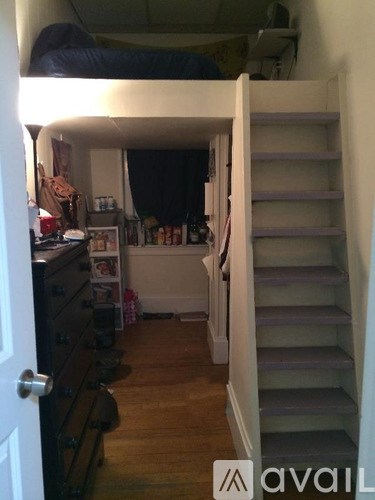 A room with a staircase and a bed in the background.