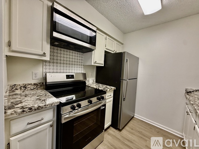 A kitchen with white cabinets and a marble countertop.
