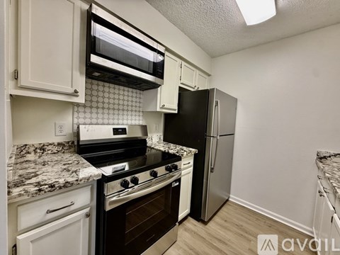 A kitchen with white cabinets and a marble countertop.