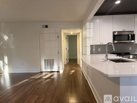 A kitchen with white cabinets and a wooden floor.