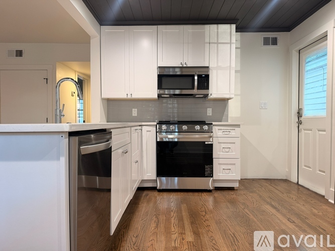 A kitchen with white cabinets and a wooden floor.