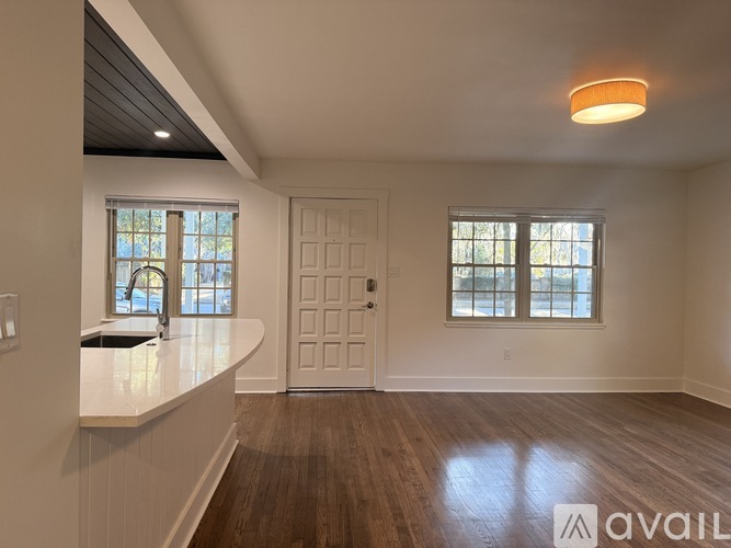 A spacious room with wooden floors and a white door.