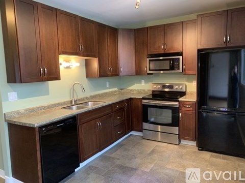 A kitchen with brown cabinets and black appliances.