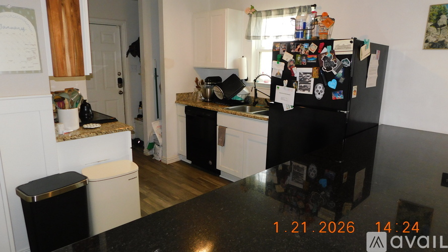 A kitchen with a black fridge and a black counter top.