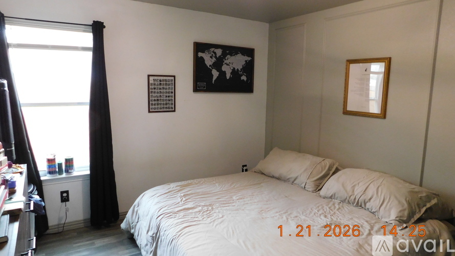 A bedroom with a bed, a window with curtains, and a world map on the wall.