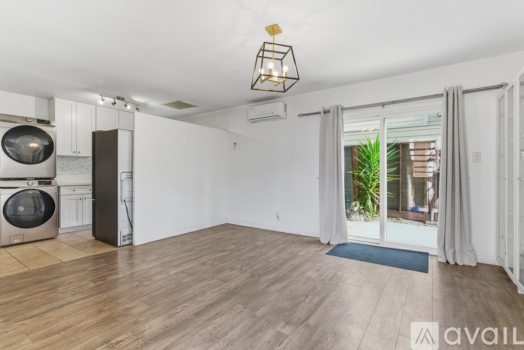 A room with wooden flooring and a large window with a view of a building outside.