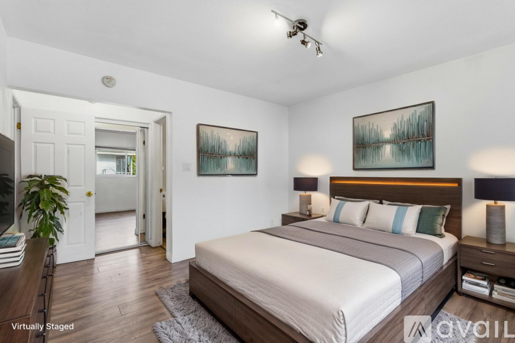 A bedroom with a large bed and two lamps.