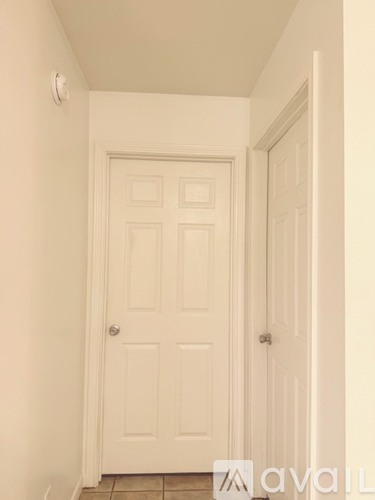 A white door in a hallway with a tiled floor.