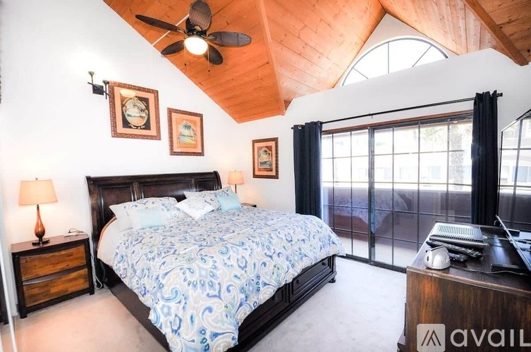A bedroom with a large bed and a ceiling fan.
