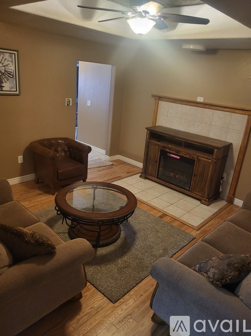 A living room with a brown couch, a brown chair, and a glass coffee table.