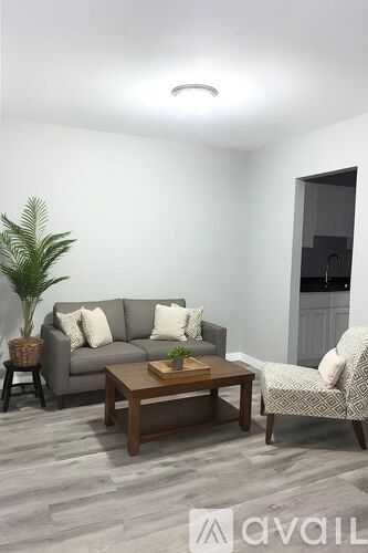 A living room with a grey couch, a wooden coffee table, and a plant.