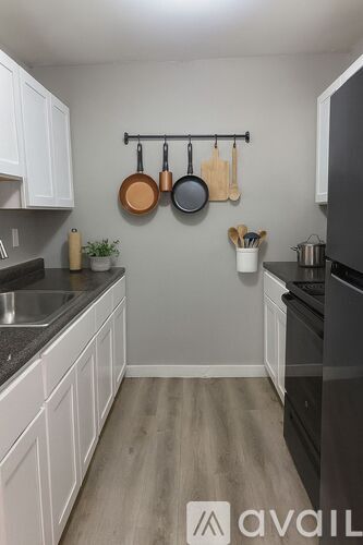 A kitchen with white cabinets and a black fridge.