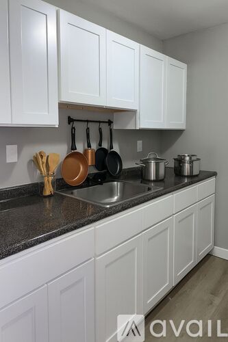 A kitchen with white cabinets and a black countertop.