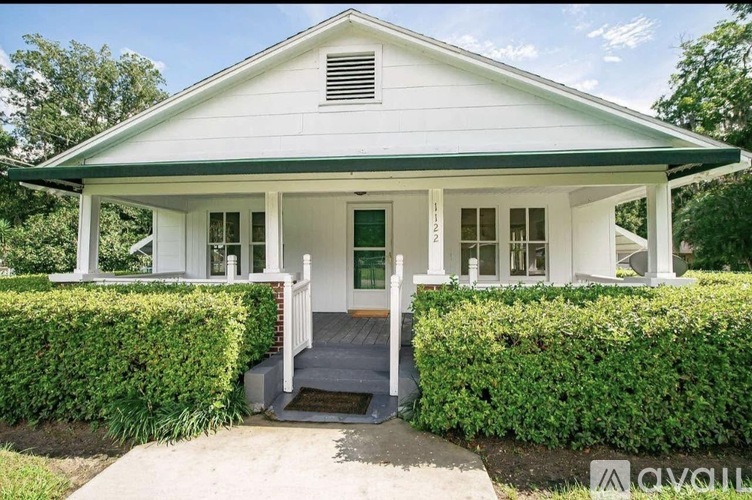 A white house with a green roof and a porch.