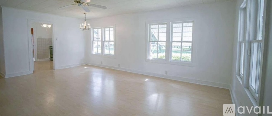A spacious room with a ceiling fan and large windows.