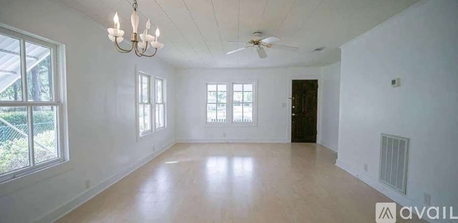 A large empty room with a chandelier and a ceiling fan.