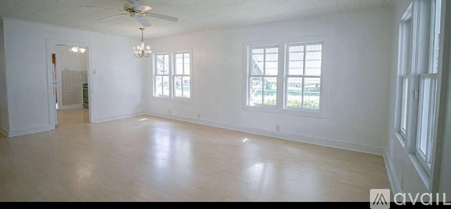 A spacious room with a ceiling fan and large windows.