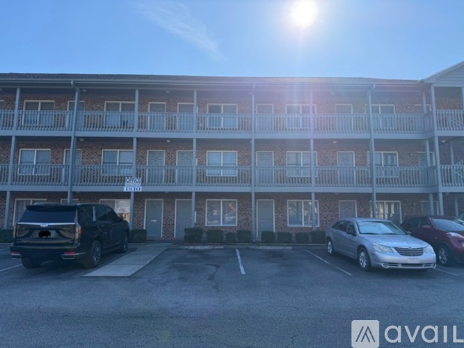 A sunny day at the apartment complex with cars parked in the lot.