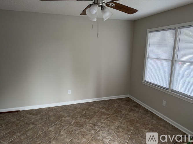 A room with a carpeted floor, a ceiling fan, and a window with blinds.