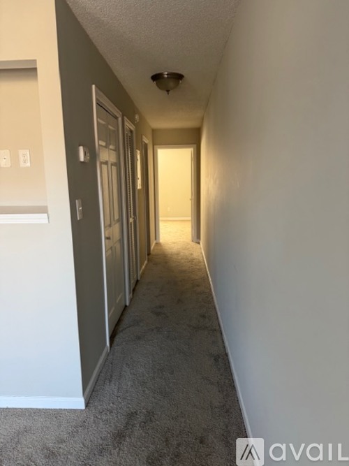 A long hallway with carpeted flooring and white walls.