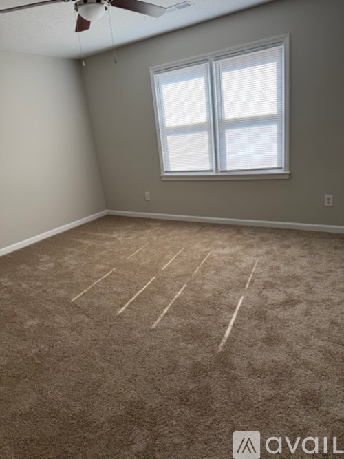 A room with a carpeted floor and a window with blinds.