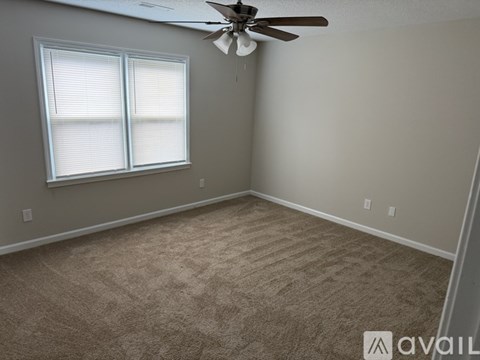 A room with a carpeted floor and a window with blinds.