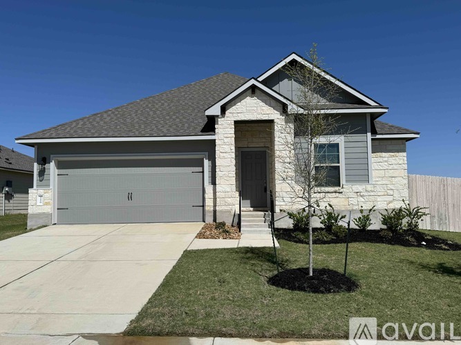A house with a garage and a tree in front.