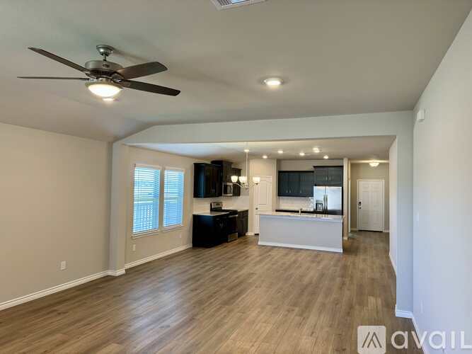 A spacious living room with a ceiling fan and hardwood flooring.