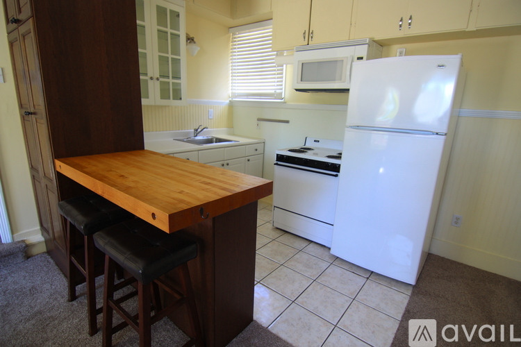 A kitchen with a white refrigerator and a wooden island with bar stools.