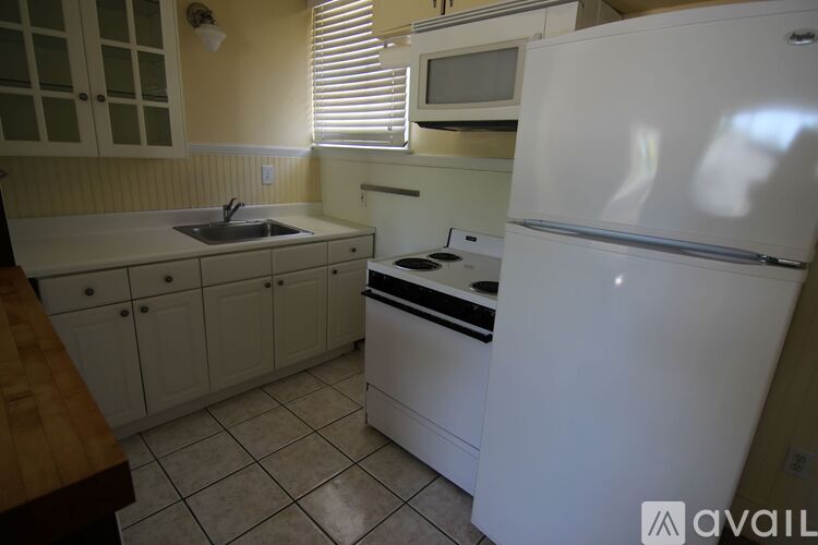 A kitchen with white appliances and a wooden counter.