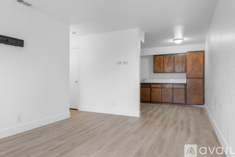 A spacious room with wooden flooring and a cabinetry unit.