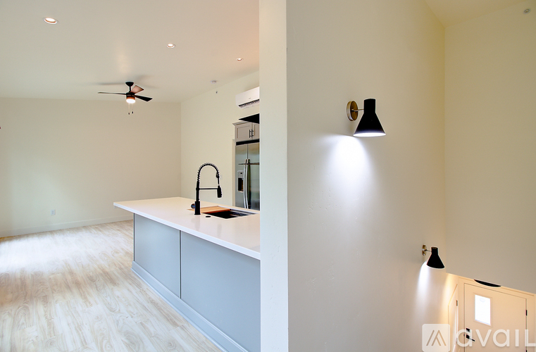 A kitchen with a white counter and a black fan on the ceiling.