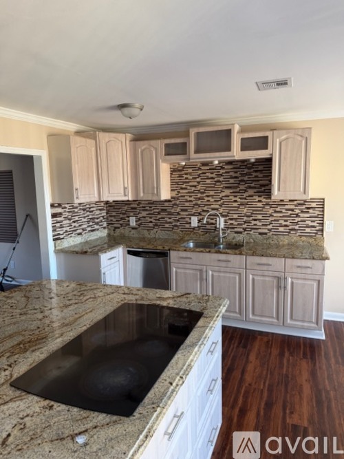 A kitchen with a granite countertop and wooden cabinets.