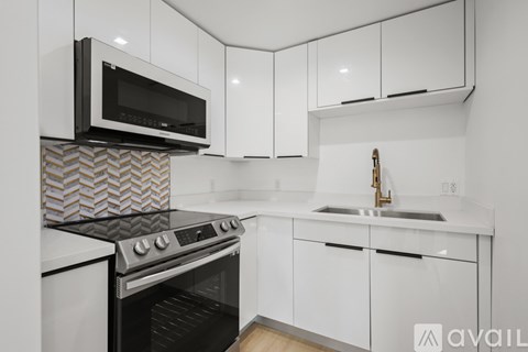 A modern kitchen with white cabinets and a black microwave above the stove.