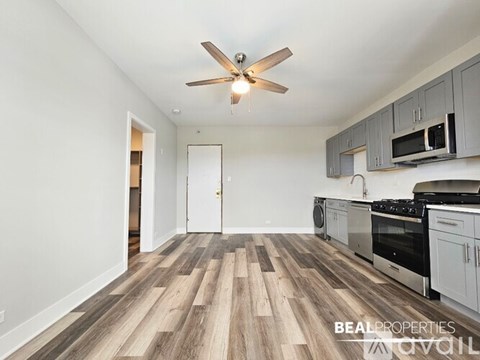 A kitchen with a fan on the ceiling and wooden flooring.
