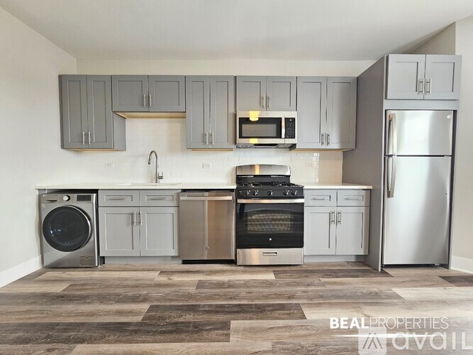 A modern kitchen with stainless steel appliances and grey cabinets.