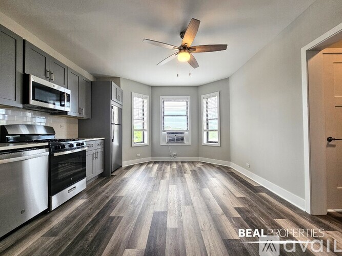 A spacious kitchen with a wood floor and a ceiling fan.