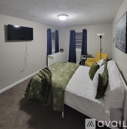 A bedroom with a bed, a television, and a lamp.