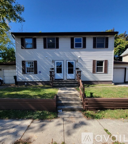 A two-story house with a white exterior and a brown door.