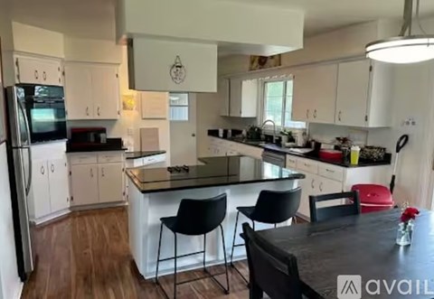 A kitchen with white cabinets and a black island.