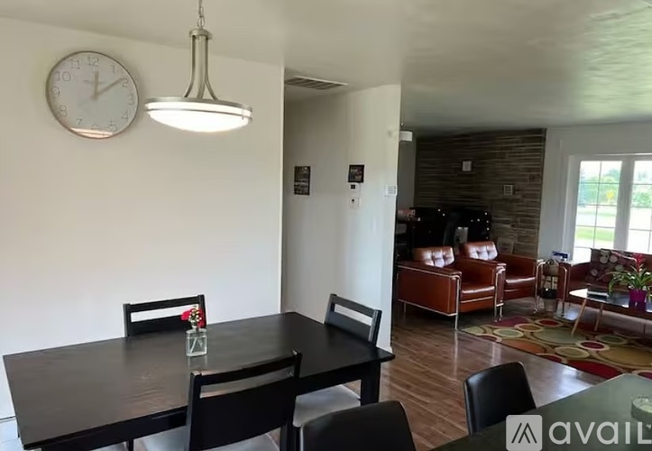 A dining room with a table and chairs and a clock on the wall.
