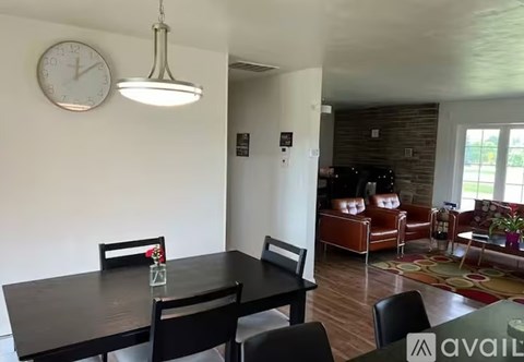 A dining room with a table and chairs and a clock on the wall.
