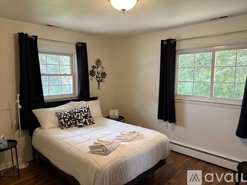 A bedroom with a white bed and black curtains.