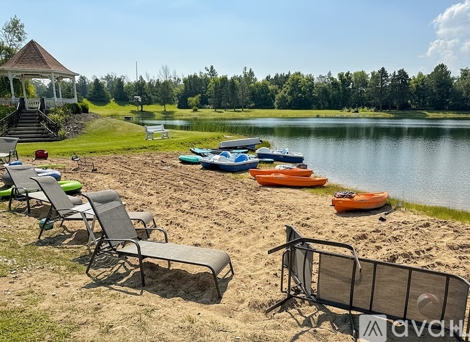 A beach scene with chairs, a gazebo, and boats on the water.